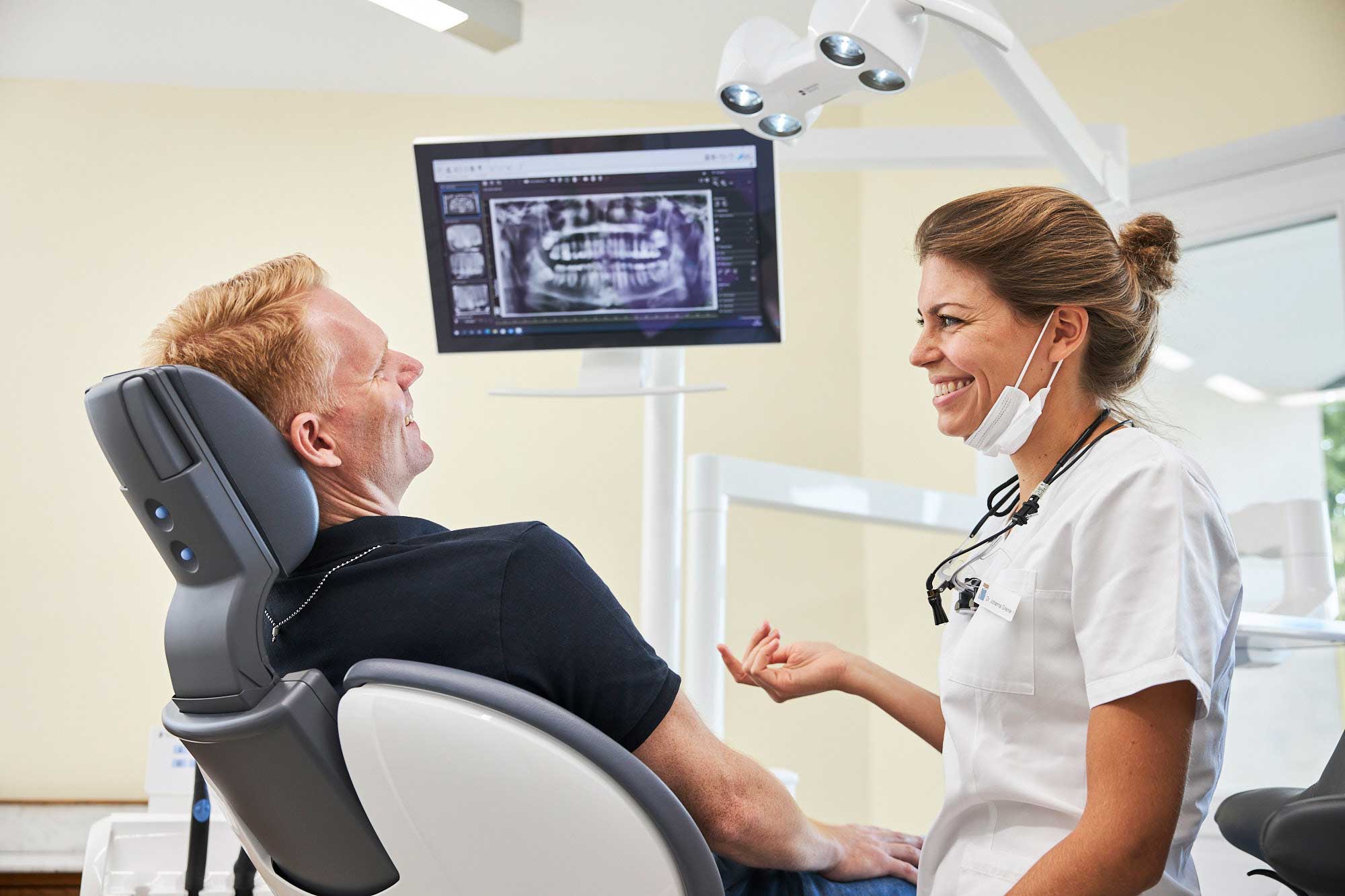 Zahnärztin bespricht Röntgenbild mit dem Patienten