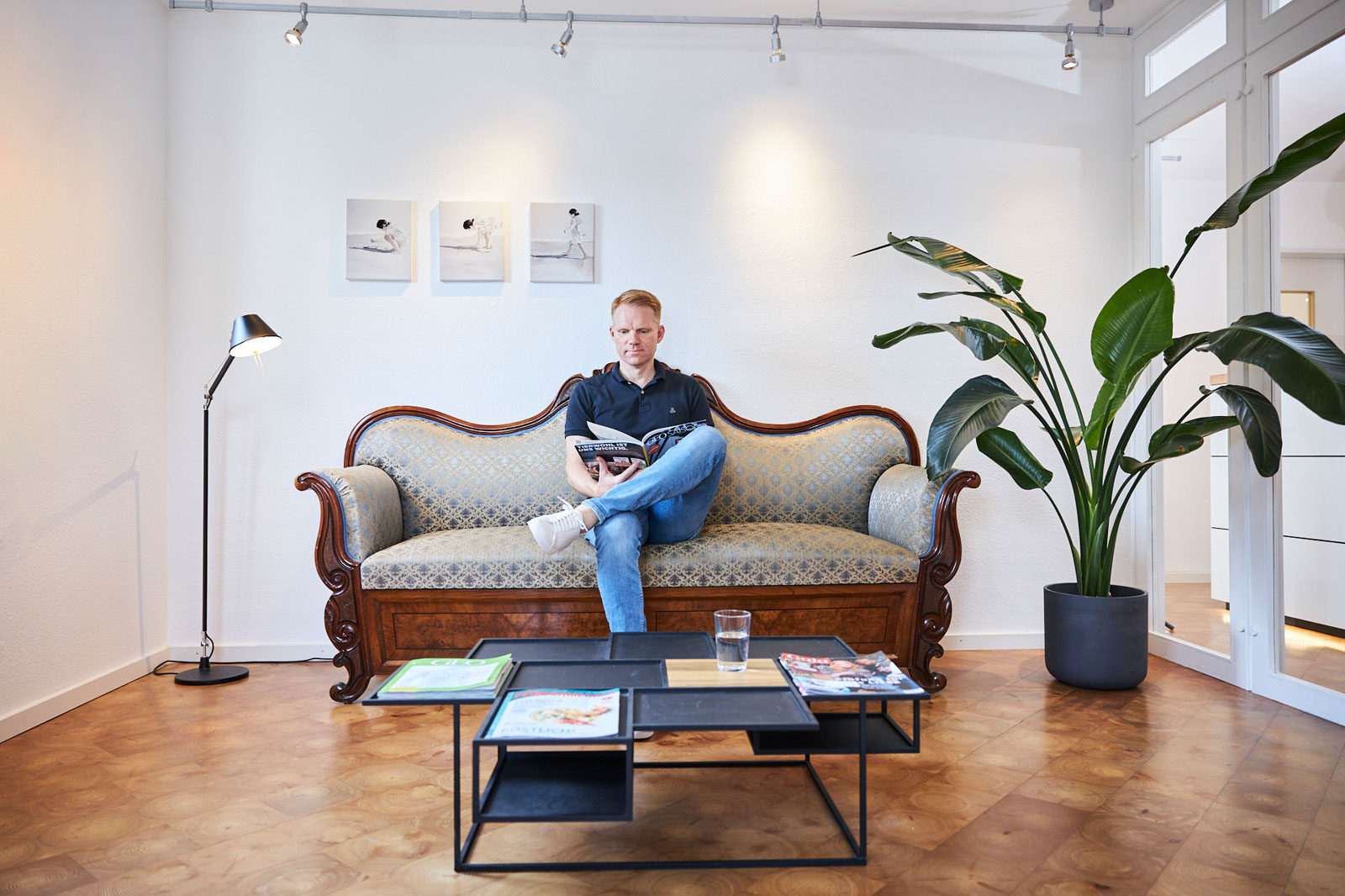 Patient sitzt im Wartezimmer auf der Couch und blättert eine Zeitschrift durch